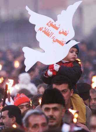 12/25-ベツレヘムのクリスマス行進、鳩のカードには「我々は闇を照らすロウソクである」と書いてある